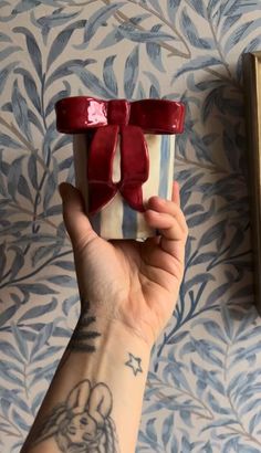 a woman's hand holding a gift wrapped in red ribbon