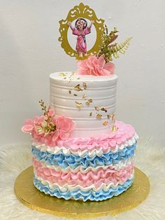 a multi layer cake decorated with pink, blue and white ruffles on a gold platter