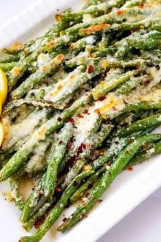 asparagus with parmesan cheese and lemon wedges on a white plate