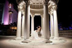 a bride and groom kissing in front of an ornate gazebo at night