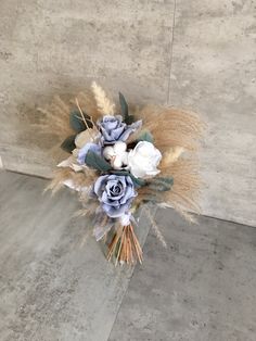 a bouquet of flowers sitting on top of a cement floor in front of a wall