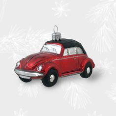 a red car ornament with a santa hat on it's top and snowflakes in the background