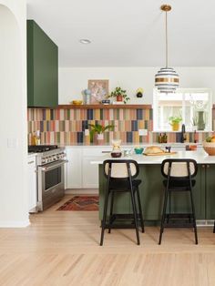 two stools sit in front of the kitchen island with an island countertop and colorful tile backsplash