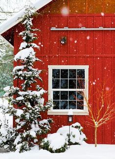 a red barn with snow falling on it