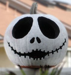 a white pumpkin decorated with black eyes and a jack - o'- lantern face