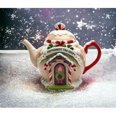 a teapot shaped like a house with candy canes on the roof and snowflakes in the background