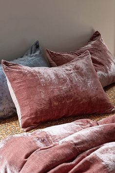 the bed is covered with pink and grey pillows