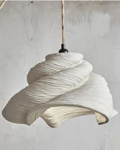 a white light fixture hanging from a rope