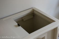 the corner of a white cabinet with a black handle on it's left side