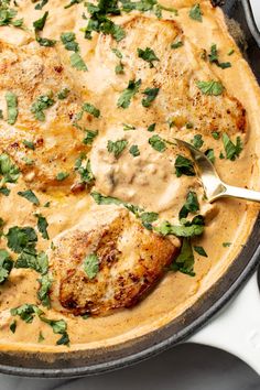 a skillet filled with chicken covered in gravy and garnished with cilantro