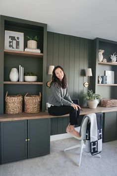 a woman sitting on top of a desk in front of bookshelves and shelves