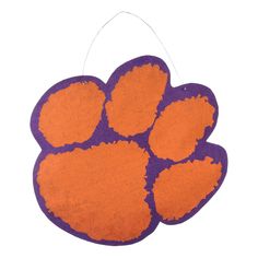 an orange and purple dog paw ornament hanging from a string on a white background