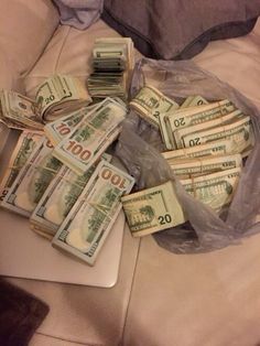 a pile of money sitting on top of a laptop computer