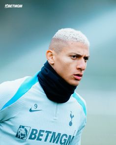 a close up of a soccer player wearing a blue jersey and black neck gaiter