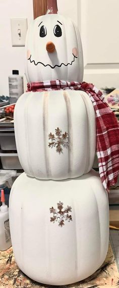 three white pumpkins stacked on top of each other in the shape of a snowman