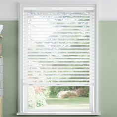 an empty room with green walls and white blinds