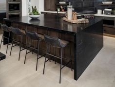 a kitchen with black counter tops and stools next to an island in the middle