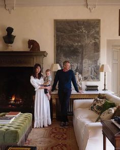 a man, woman and child are standing in a living room with a fire place