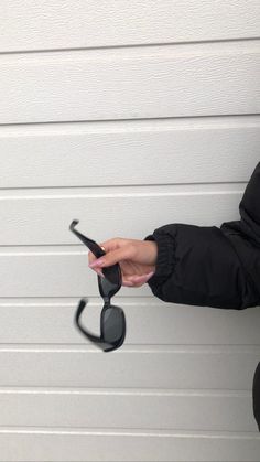 a woman holding a cell phone in her right hand while standing next to a garage door