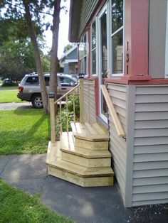 a porch with steps leading to the front door and car parked in the driveway behind it