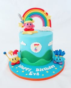 a blue birthday cake with rainbows and clouds on the top is for a child's first birthday