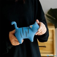 a person holding a blue stuffed animal in their left hand and wearing a black shirt