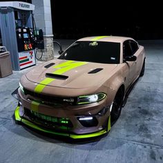 a brown and yellow car parked in front of a gas station at night with neon stripes