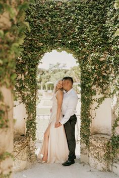 a bride and groom kissing in an archway covered with ivys at their wedding reception