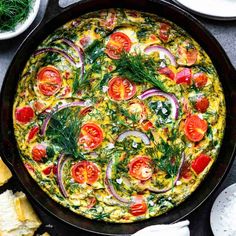 an omelet with tomatoes, onions and herbs in a cast iron skillet