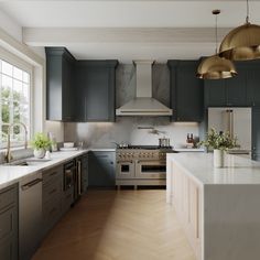 a kitchen with gray cabinets and white counter tops, gold pendant lights over the stove