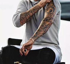 a man with tattoos on his arm sitting down