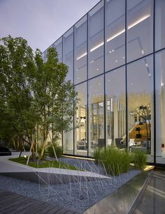 a glass building with trees and plants in front of it