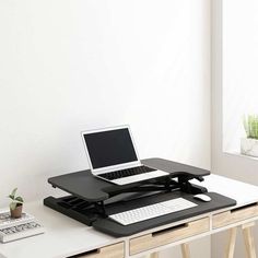 a laptop computer sitting on top of a black and white desk with a wooden drawer underneath it