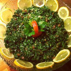 a bowl filled with lemons and greens on top of a wooden table