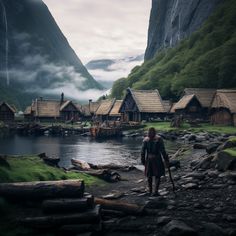 a man standing in the middle of a lake surrounded by mountains and houses with thatched roofs