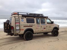 the truck is parked on the beach by the water