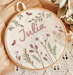 a cross stitch pattern with the word julia in pink and white daisies on it