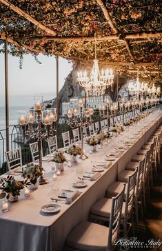 an outdoor dining area with tables and chandeliers set up for a formal function