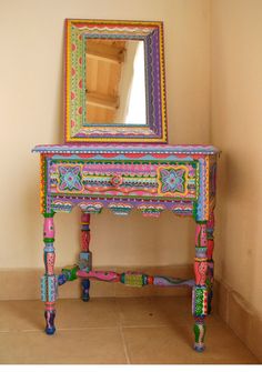 a colorful wooden table with a mirror on it