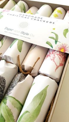 an assortment of candles in a box with floral designs on the wrappers and packaging