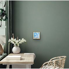 a room with green walls and a white table in front of the window is filled with flowers