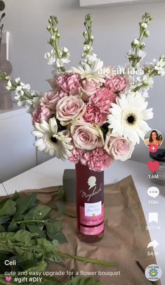 a vase filled with pink and white flowers on top of a table next to a brown bag