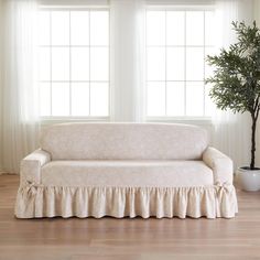 a white couch sitting next to a potted plant on top of a hard wood floor