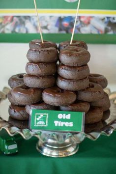 a stack of chocolate donuts sitting on top of a green tablecloth covered tray