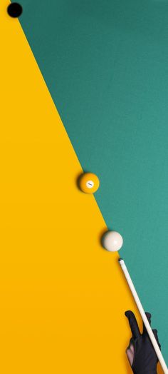 a person is playing pool on a yellow and green surface with two white balls in the air