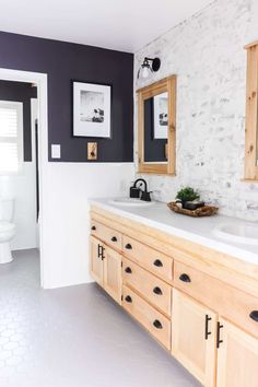 a bathroom with white and black walls, wooden cabinets and a large mirror on the wall