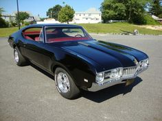 an old black car parked in a parking lot