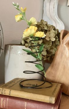 a vase filled with yellow flowers sitting on top of a table next to a stack of books