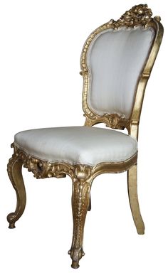 an ornately decorated chair with white upholstered seat and gold trimmings