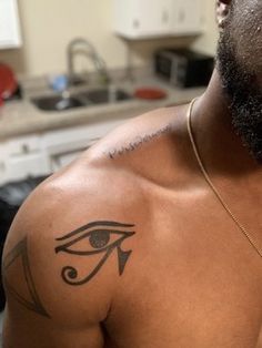 a man with an eye tattoo on his upper arm and chest is looking at the camera